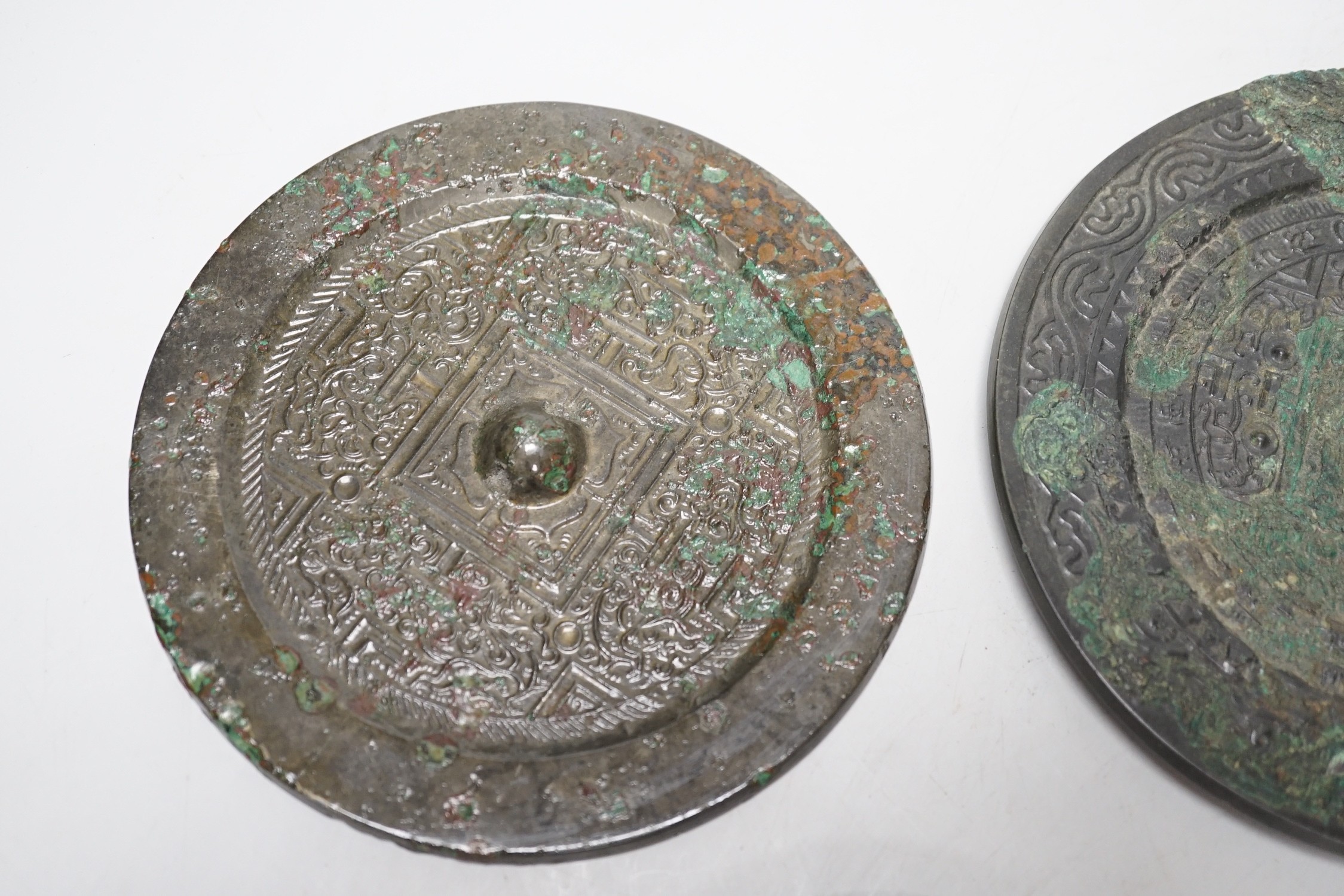 A group of six Chinese archaic bronze mirrors, including two Han dynasty TLV mirrors, and a Tang dynasty squirrel and vine small mirror, five corroded, largest 14cm diameter
